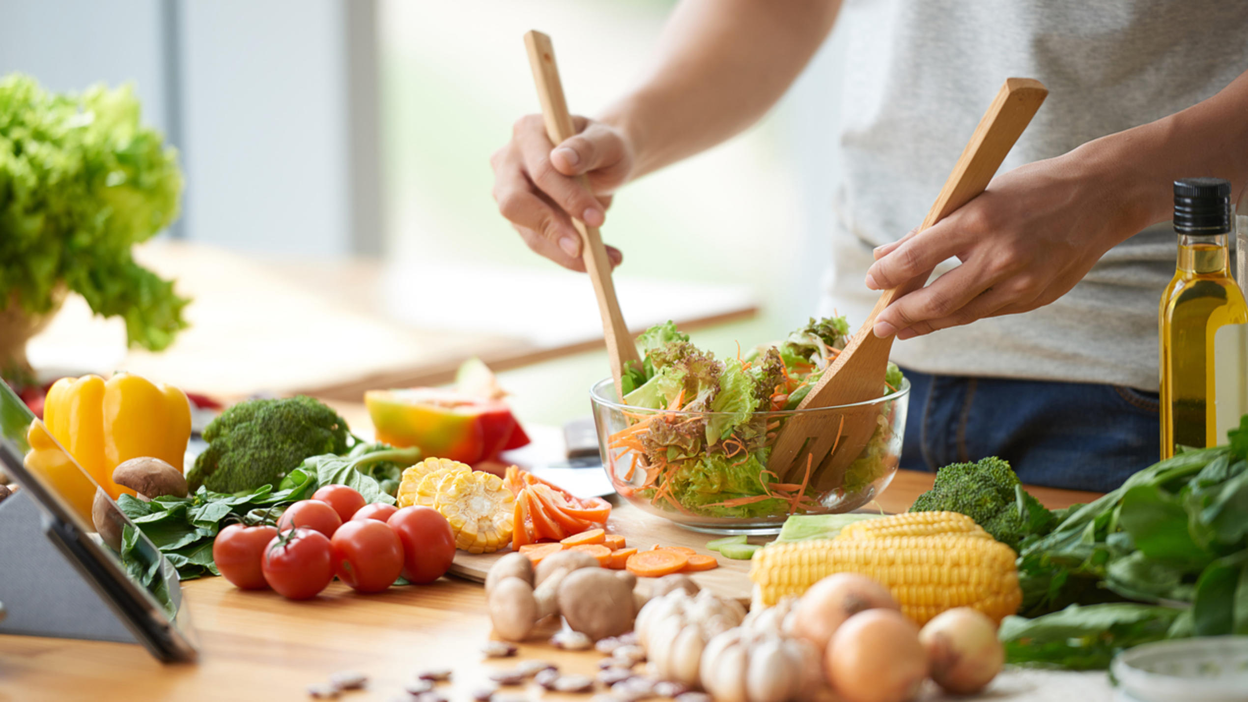Pflanzliche Ernährung kann Darmkrebsrisiko um 22 Prozent senken - aber nur bei Männern! Vegetarian man mixing vegetable salad in bowl
Ein Mann mischt einen Salat in einer Salatschüssel. Vor ihm auf dem Tisch liegt Gemüse.