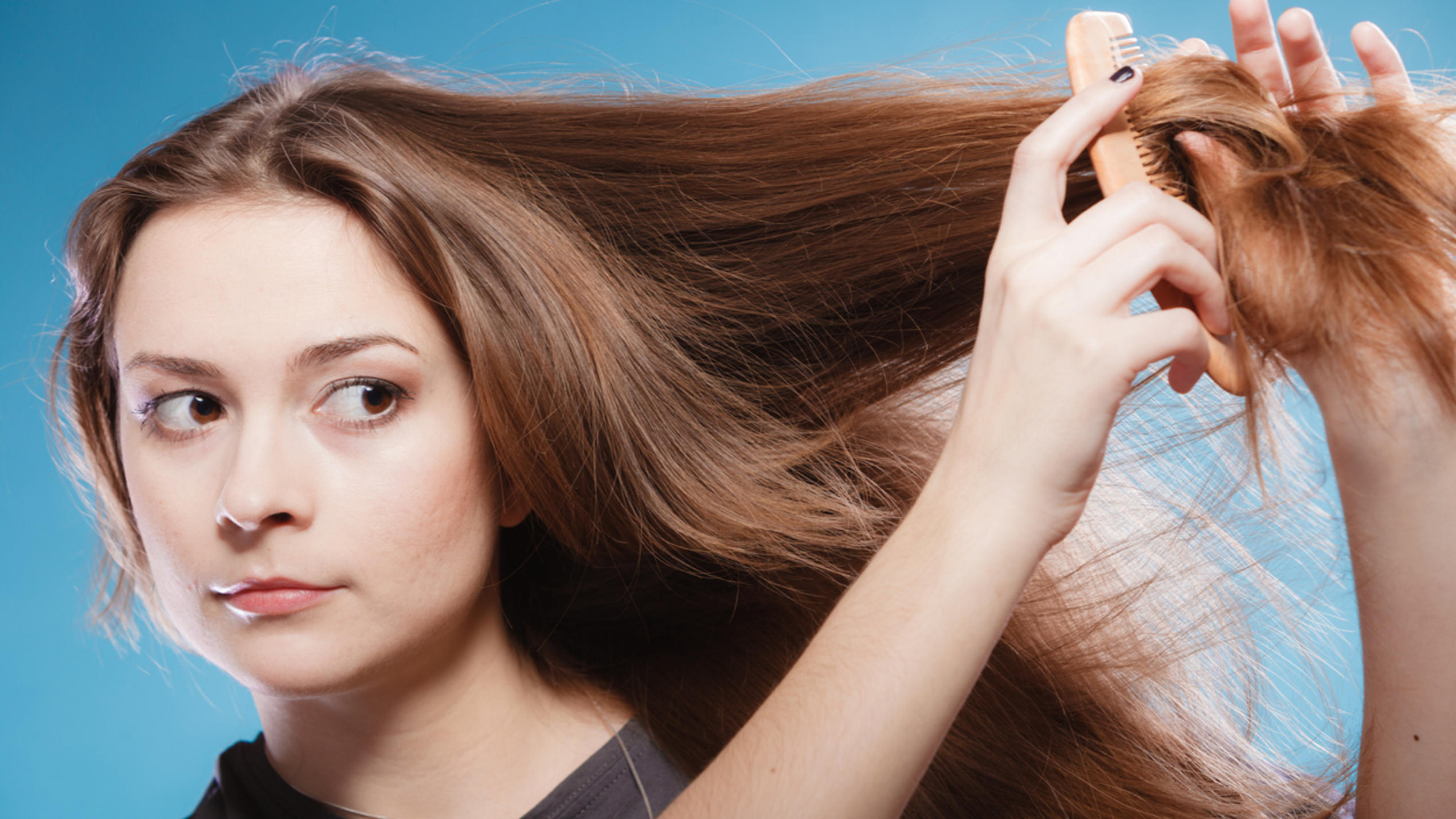 Das hilft gegen trockene Haare durch Heizungsluft Frau kämmt sich trockene Haare