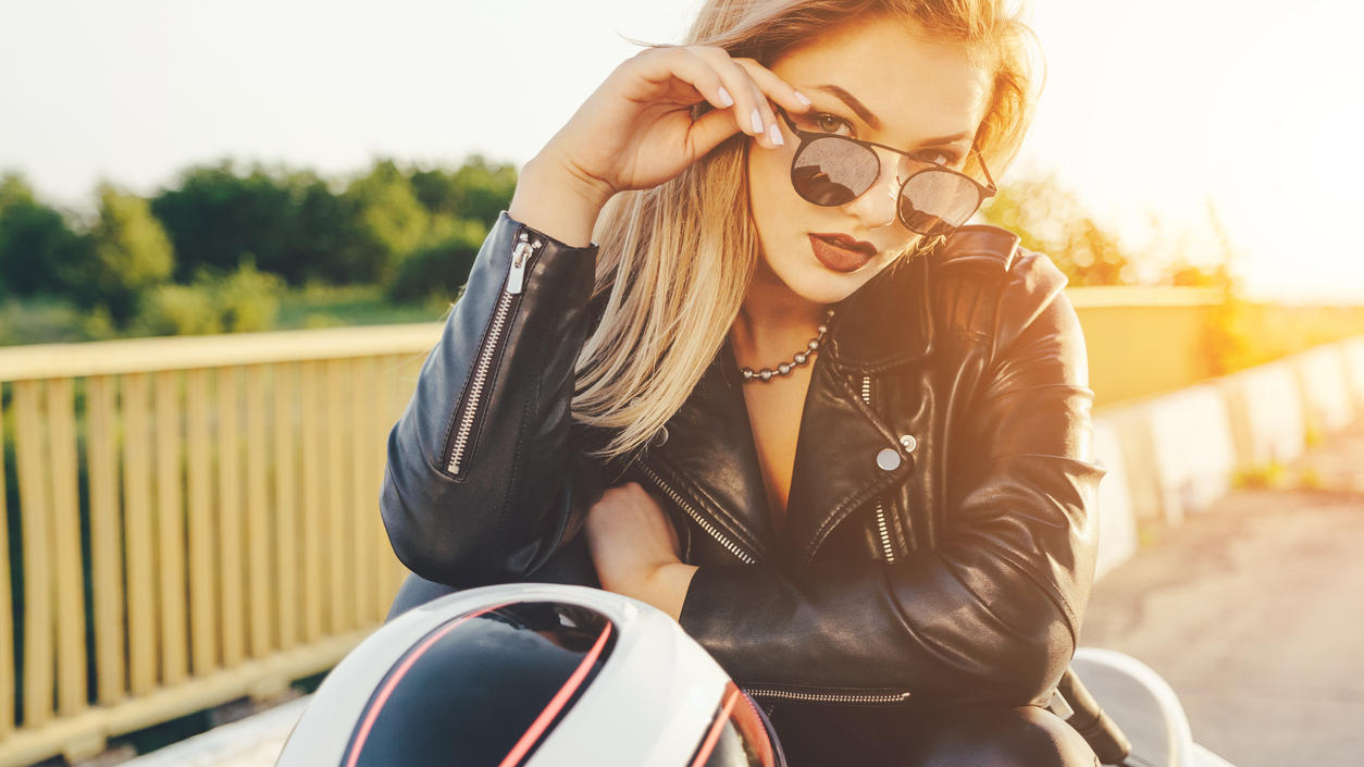 Fashion Lexikon: Bikerjacke Blonde Frau in Bikerjacke auf einem Motorrad