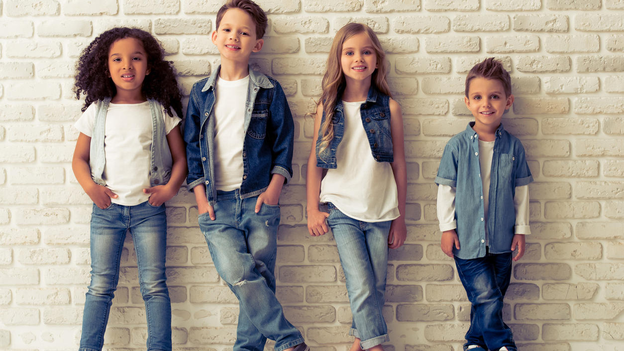 Fashion Lexikon: Denim Vier Kinder tragen verschiedene Outfits aus dem Stoff Denim.