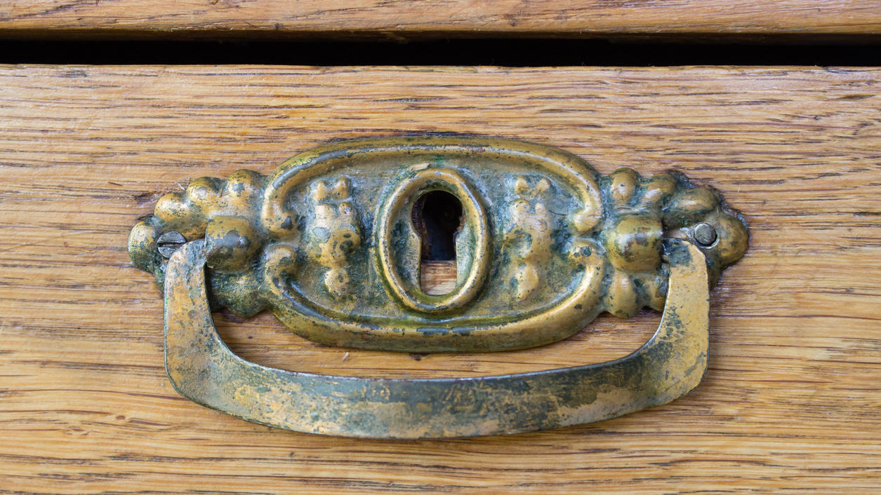 Fashion Lexikon: Patina Hier ist ein alter kupferner Möbelgriff zu sehen. Auf dem Möbelgriff hat sich Patina abgesetzt.