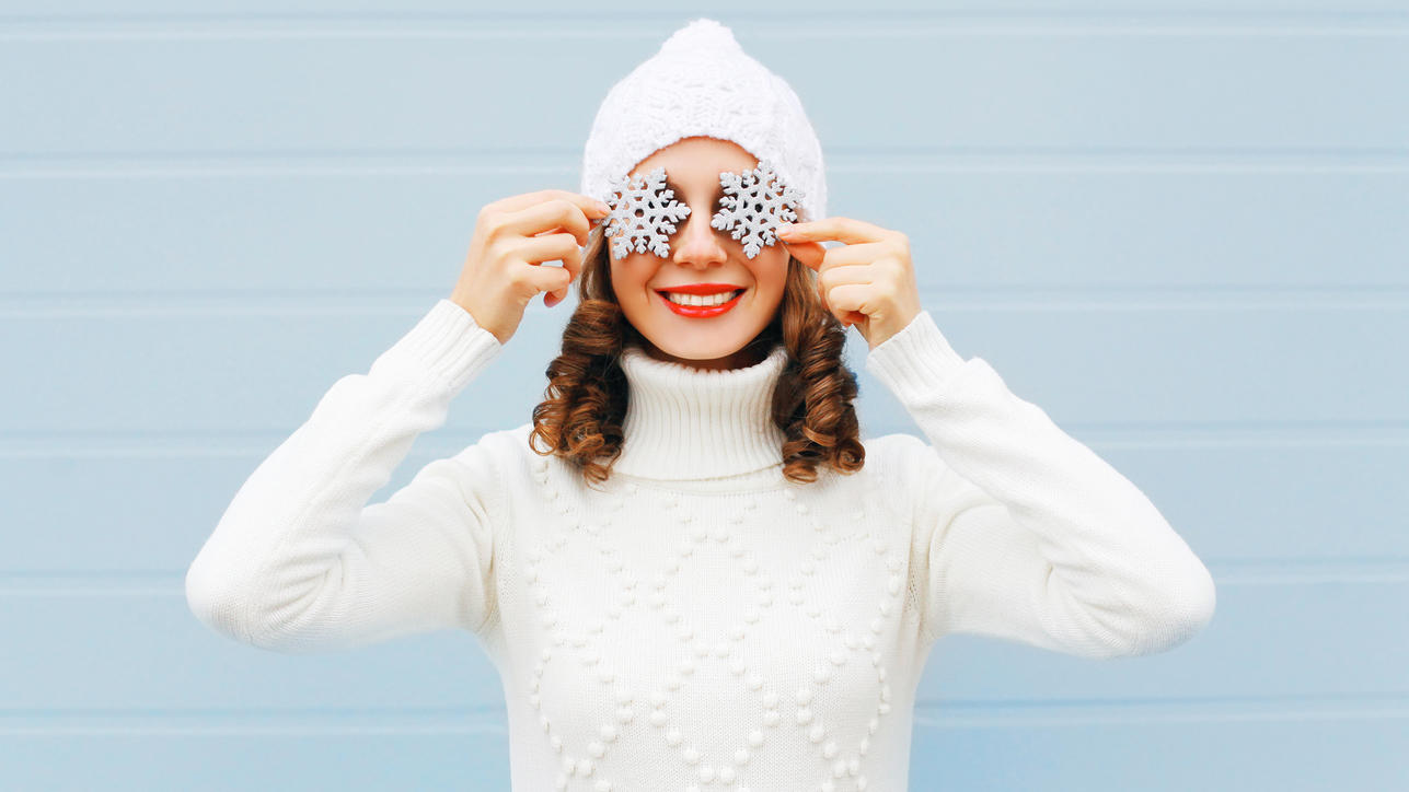 Fashion Lexikon: Strickpullover Hier ist eine junge Frau in weißem Strickpullover mit passender Strickmütze zu sehen.