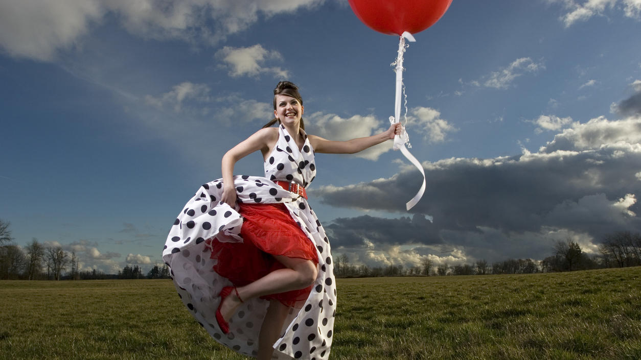 Fashion Lexikon: Petticoat Model mit einem roten Petticoat unter einem Kleid im Stil der 1950er-Jahre