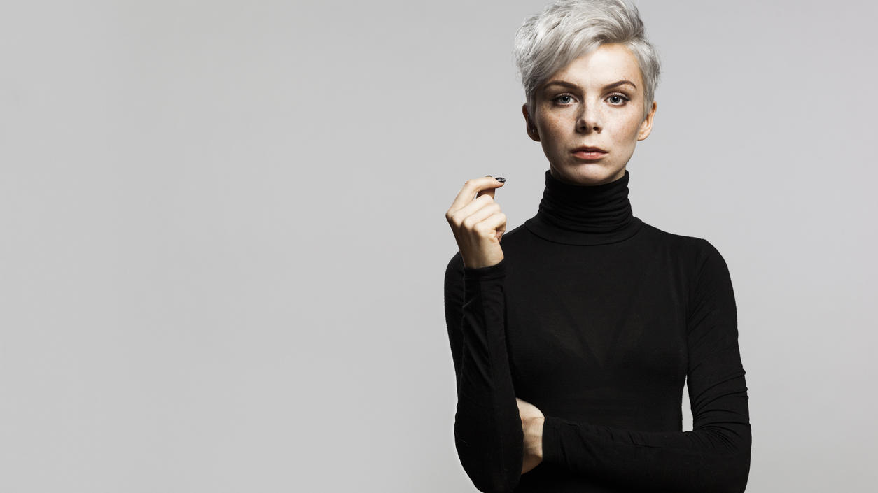 Fashion Lexikon: Rollkragen Model mit kurzen grauen Haaren trägt einen schwarzen eng anliegenden Rollkragenpullover