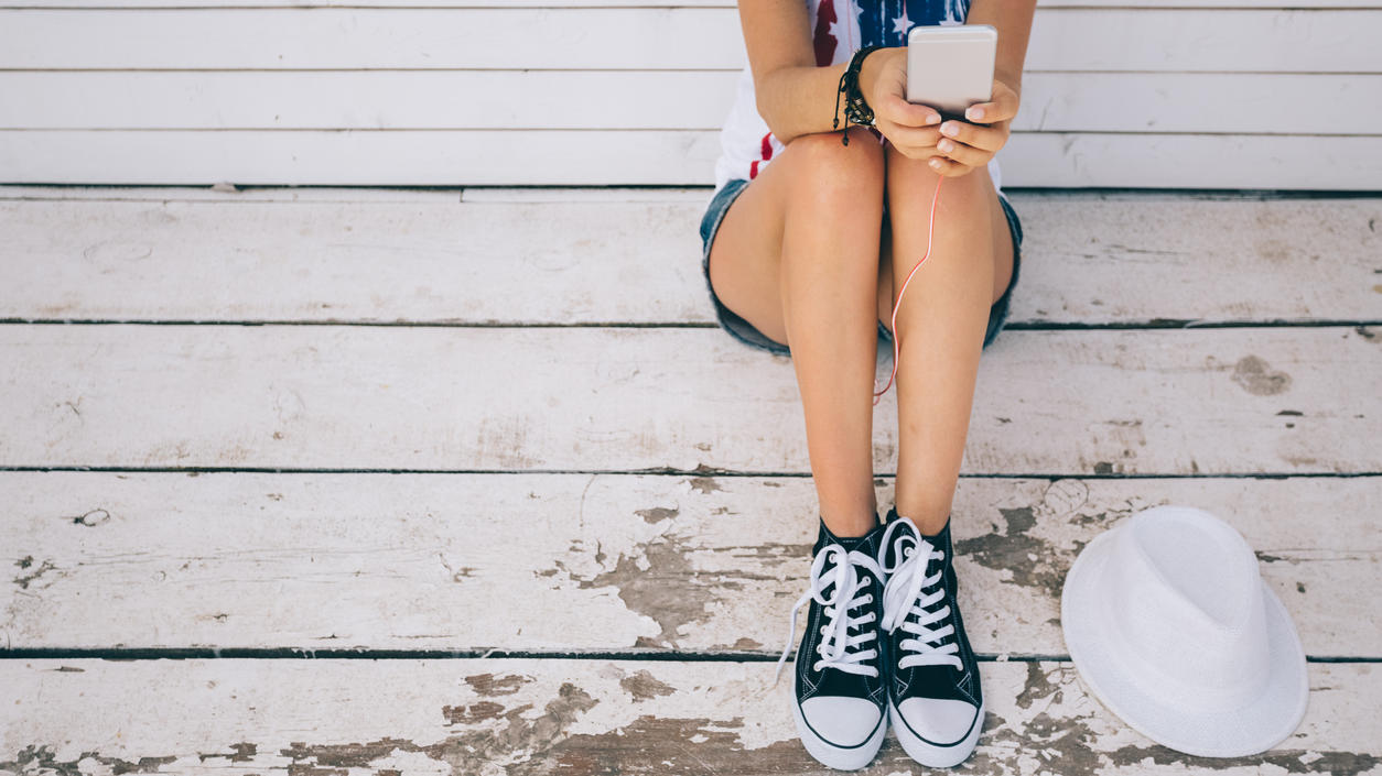 Fashion Lexikon: Chucks Frau trägt Chucks mit Handy in der Hand
