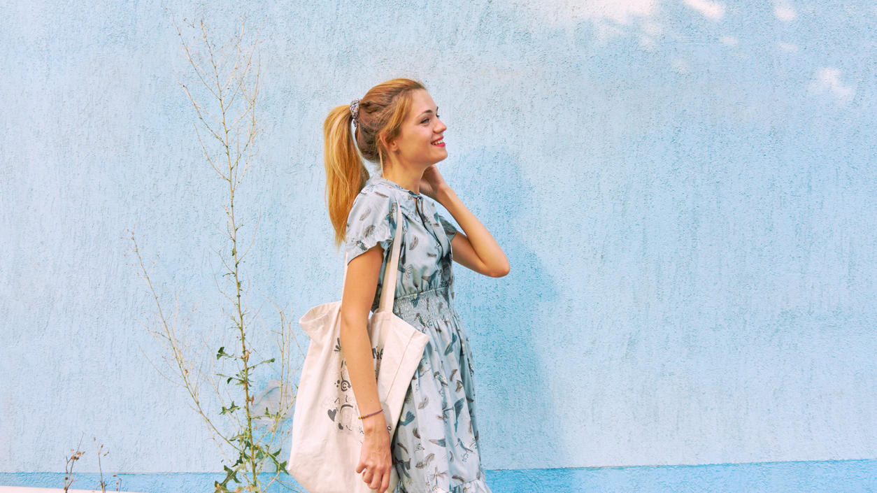 Fashion Lexikon: Tote Bag Mädchen im hellblauen Kleid mit einer weißen Tote Bag aus Baumwolle