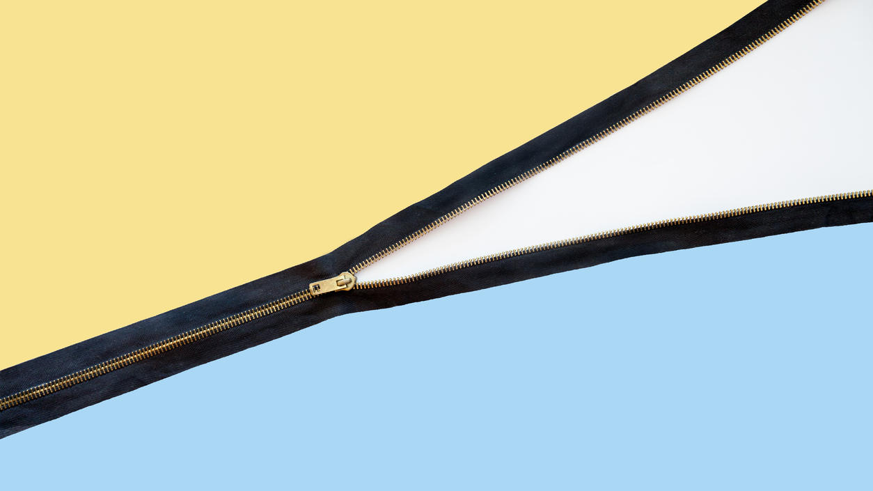 Fashion Lexikon: Zipper Halb geöffneter Zipper zwischen gelbem und blauem Stoff