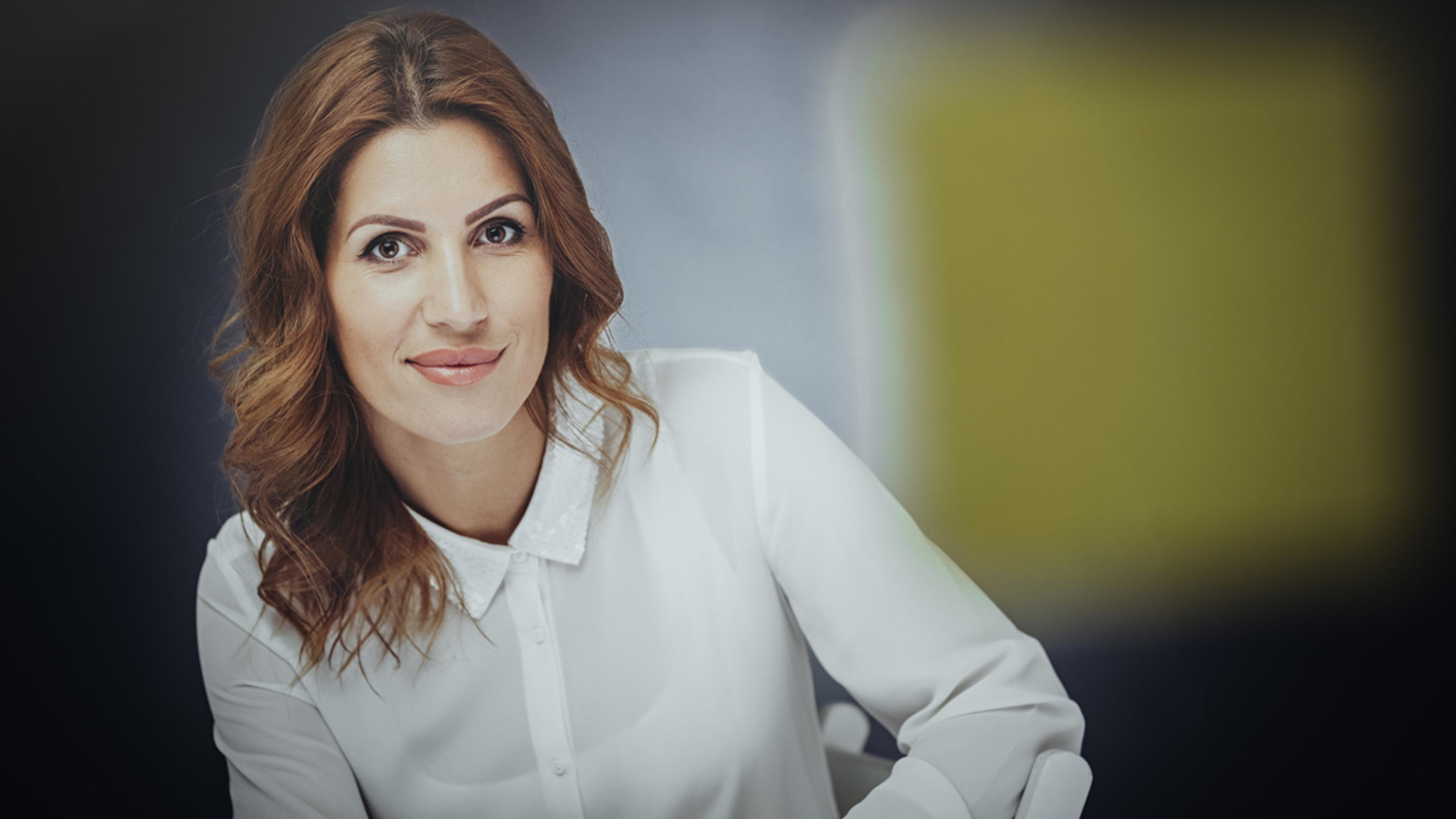 Fashion Lexikon: Minimalismus Selbstbewusste Frau mit hellbraunen Haaren und weißem Hemd im minimalistischen Style..
