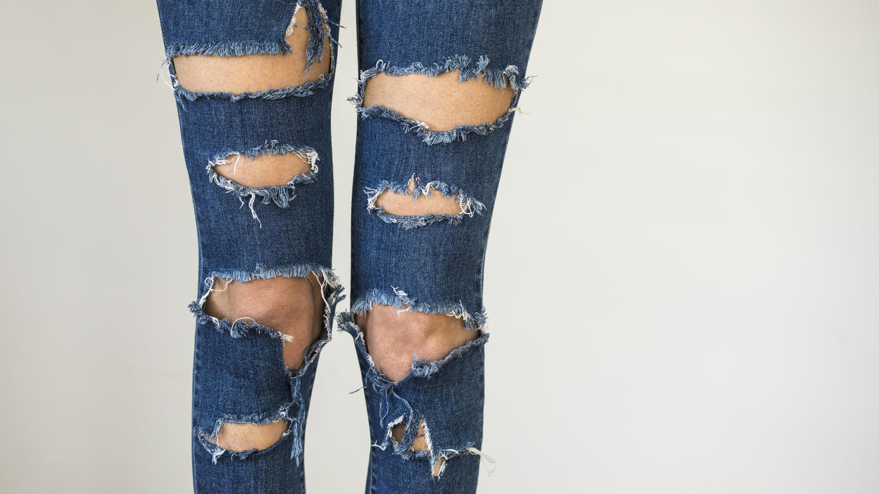 Fashion Lexikon: Cut Outs Eine Frau trägt eine blaue Jeans mit mehreren Cut-Outs