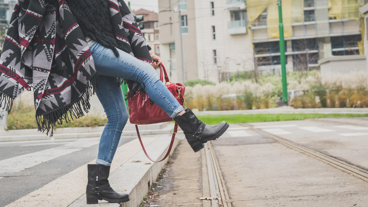 Fashion Lexikon: Biker Boots Junge Frau mit schwarzen Biker Boots und Poncho