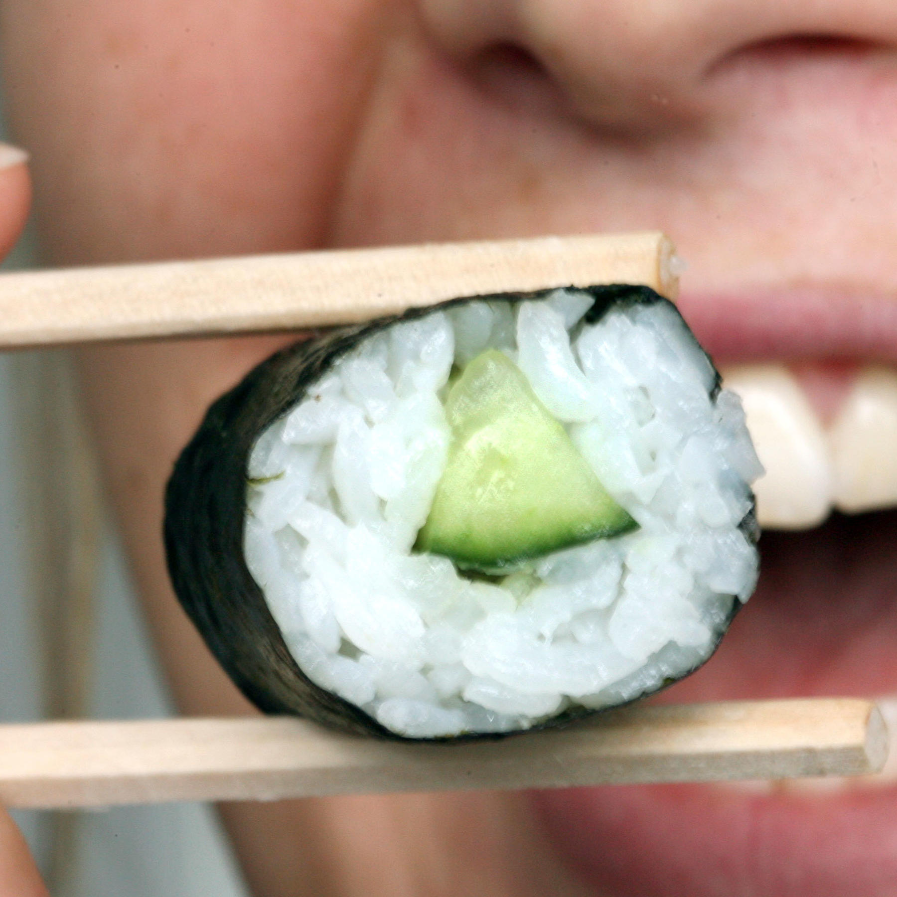 Frau hält Sushi mit Stäbchen Frau hält Sushi mit Stäbchen