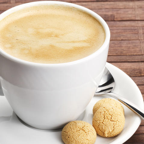 kaffee in einer weissen tasse mit einem löffel und amarettini kaffee in einer weissen tasse mit einem löffel und amarettini