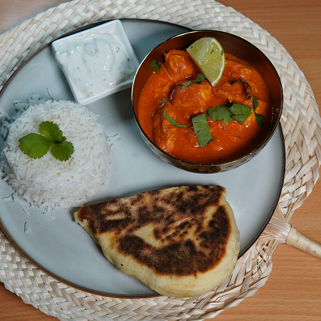 Indisches Butter-Chicken mit Reis, Naan-Brot und Gurken-Minz-Raita Indisches Butter-Chicken mit Reis, Naan-Brot und Gurken-Minz-Raita