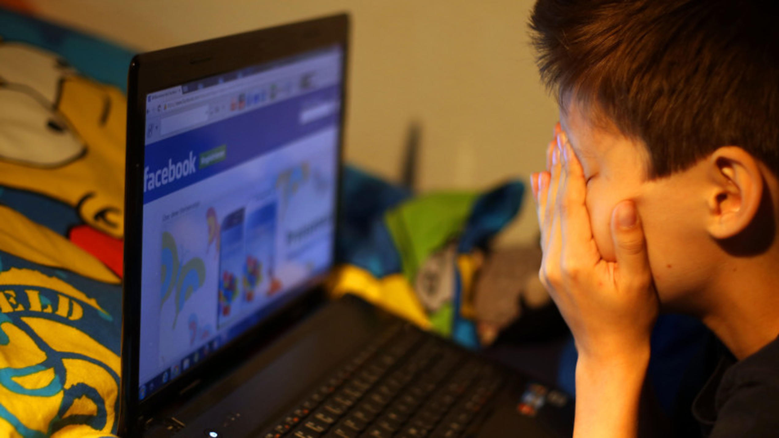 Illustration - Ein Junge reibt sich am 15.05.2013 in Leichlingen (Nordrhein-Westfalen) vor seinem Laptop beim betrachten der Facebook Seite die Augen. Eine umfangreiche Studie zum Thema Mobbing unter Kindern und Jugendlichen in Internet und sozialen 
