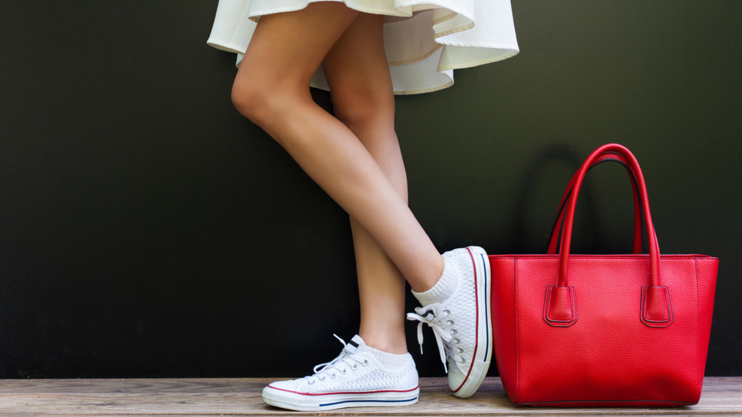 Weiße Sneaker neben roter Handtasche