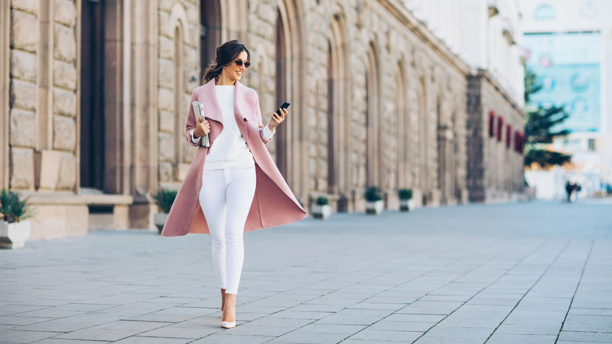 Eine elegante junge Frau ist trendy gekleidet und läuft eine Straße entlang.