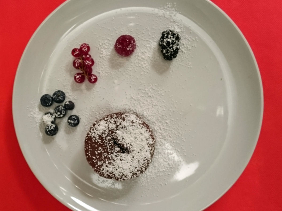 Schokoladenkuchen mit flüssigen Kern, dazu gemischte Beeren