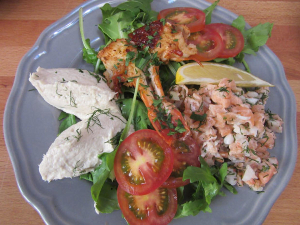 Fischmousse, Lachs-Garnelen-Tatar und Garnelen auf Tomaten-Rucola-Bett, dazu ein Baguette