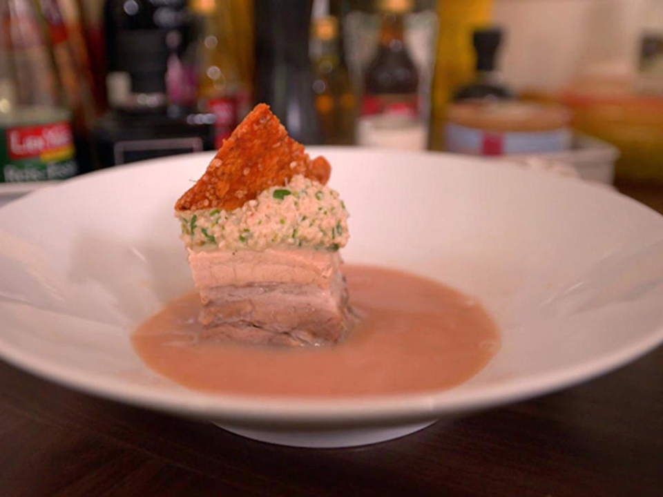 Ein Würfel vom knusprigen Schweinebauch im Yogi-Tee-Sud mit Waldorf-Salat-Nocke