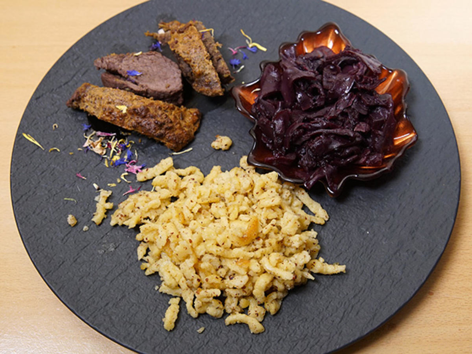 Hirschrücken unter einer Pumpernickelkruste auf Portweinjus, Nussspätzle und Apfelrotkraut