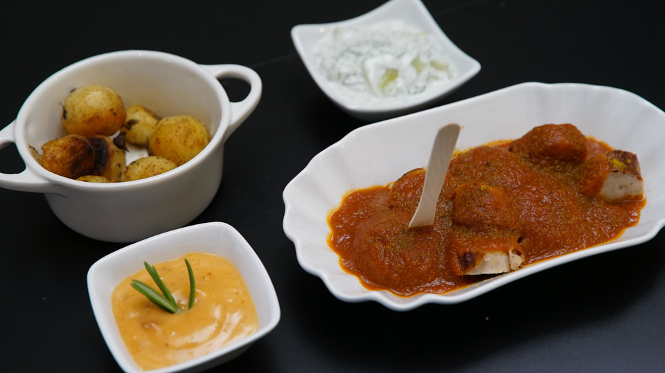 Rheinische Currywurst, Bohrkartoffeln, Pestomayonnaise und Gurkensalat