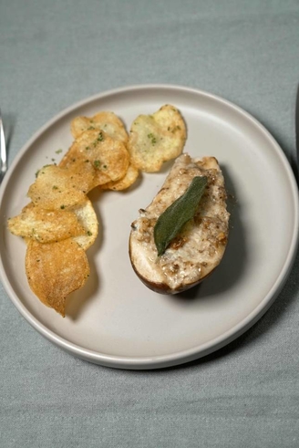 Mit Gorgonzola und Walnüssen überbackene Birne, beträufelt mit Honig, dazu Kartoffel-Salbei-Chips