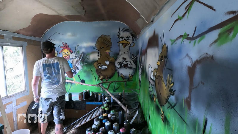 Ein Graffitti-Künstler verschönert den Bauwagen
