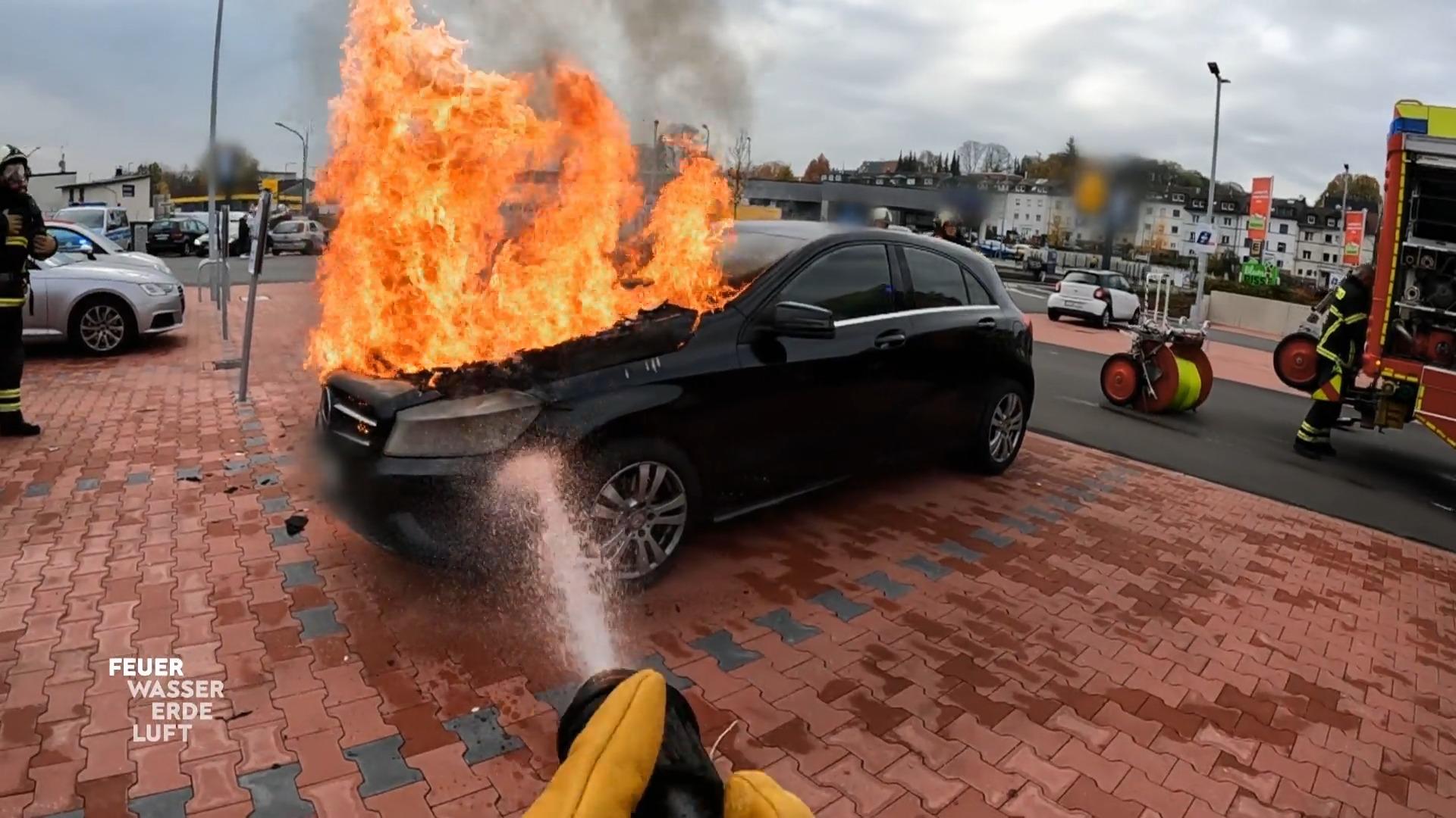 Ein brennender PKW auf einem Parkplatz