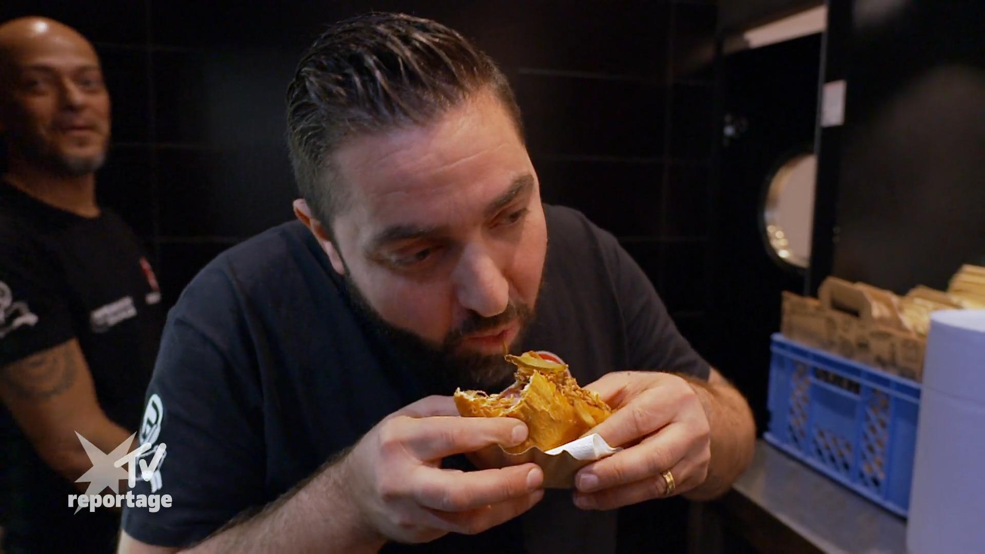 Lars präsentiert den Hot Dog seinem Geschäftspartner