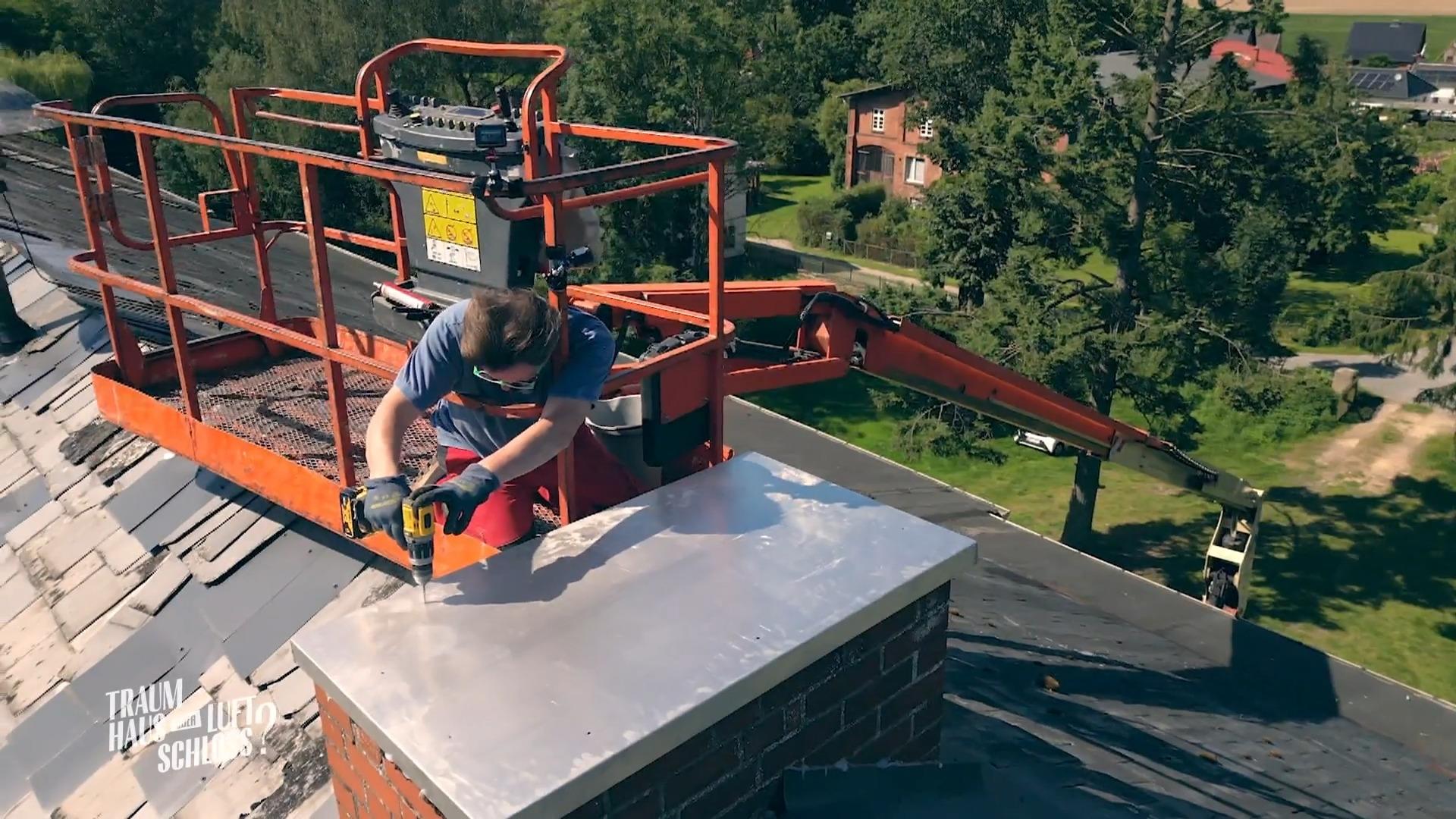Sönke bringt eine Abdeckung am Schornstein an